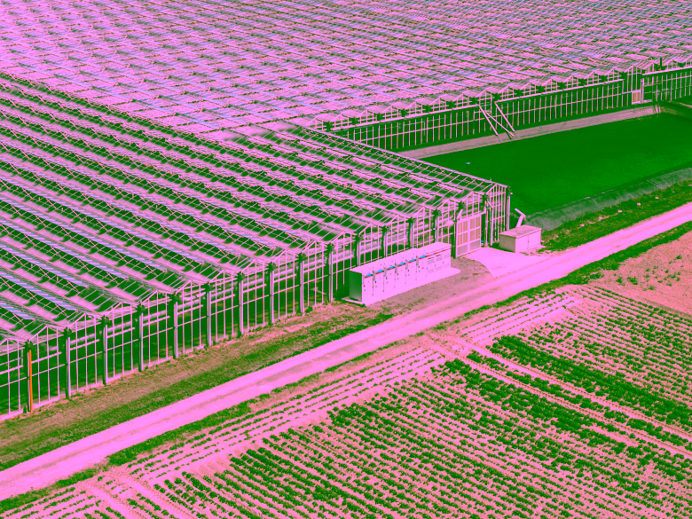 Batteriespeicher vor Gewächhaus mit Solaranlage aus Vogelperspektive